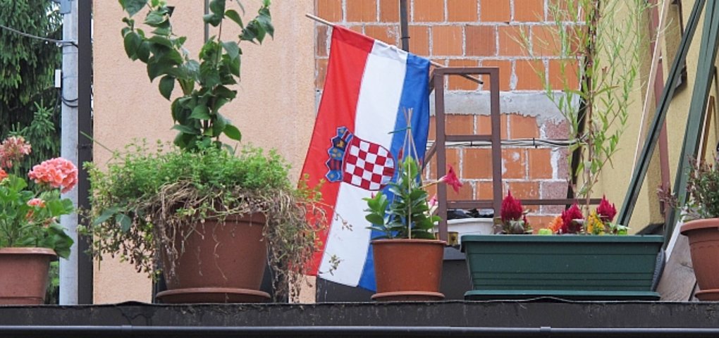Blumen neben kroatischer Flagge auf Balkon in Zagreb